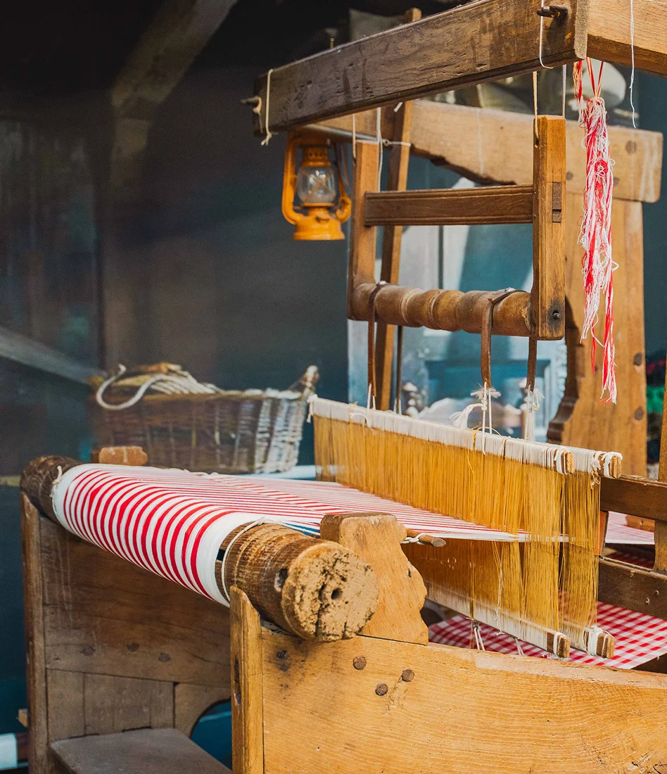 Historisch houten weefgetouw met rood-wit geweven stof in het Weverijmuseum