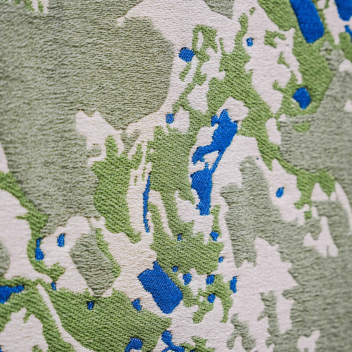 Close-up van geweven textiel met een groen, wit en blauw patroon in het Weverijmuseum.