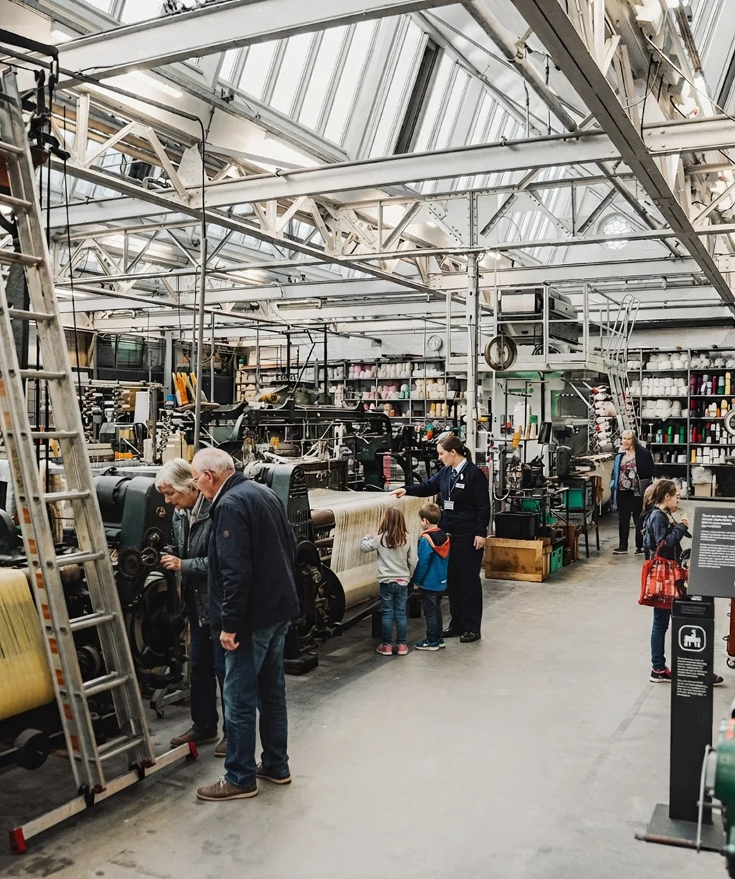 Bezoekers en gezinnen bekijken de weefmachines in het museum
