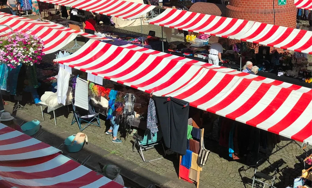 Markt met rood-wit gestreepte kramen rond een karakteristieke bakstenen toren.