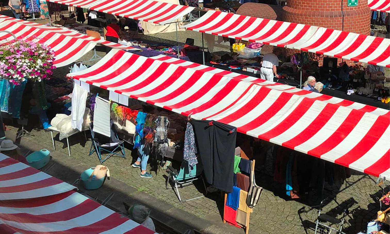 Markt met rood-wit gestreepte kramen rond een karakteristieke bakstenen toren.
