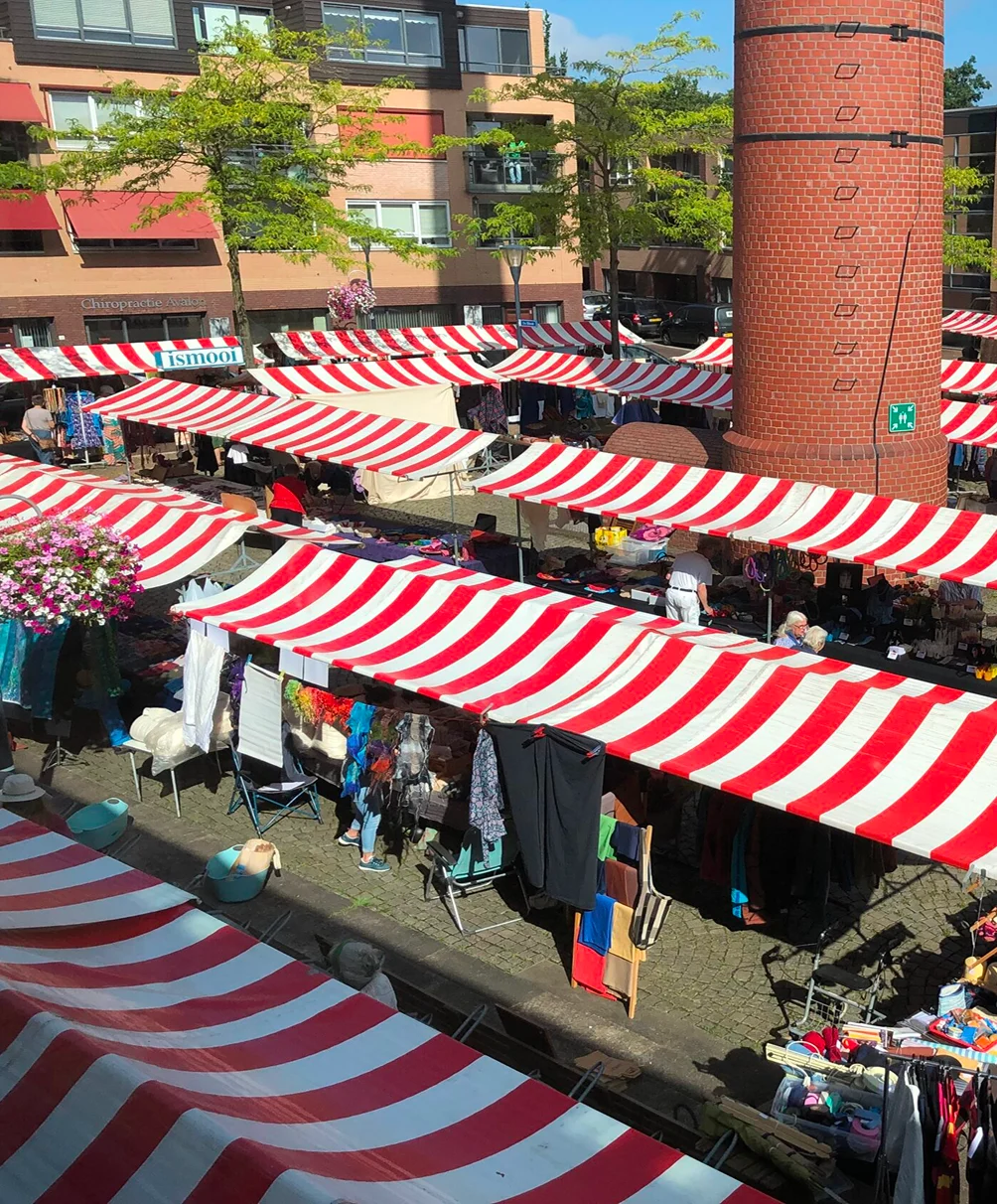 Markt met rood-wit gestreepte kramen rond een karakteristieke bakstenen toren.
