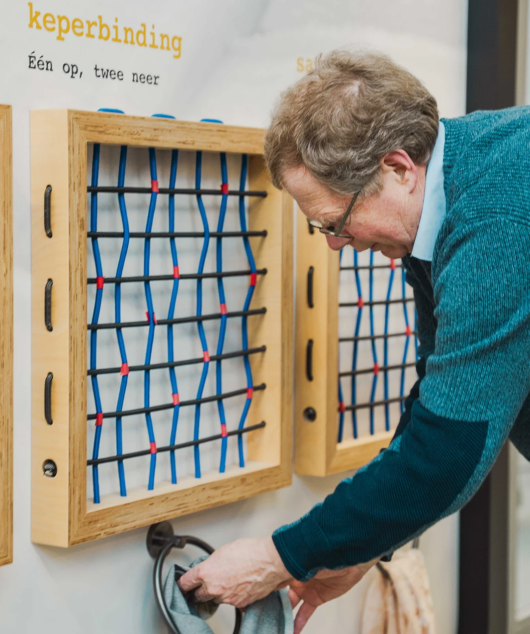 Medewerker demonstreert keperbinding bij een educatieve opstelling in het Weverijmuseum.