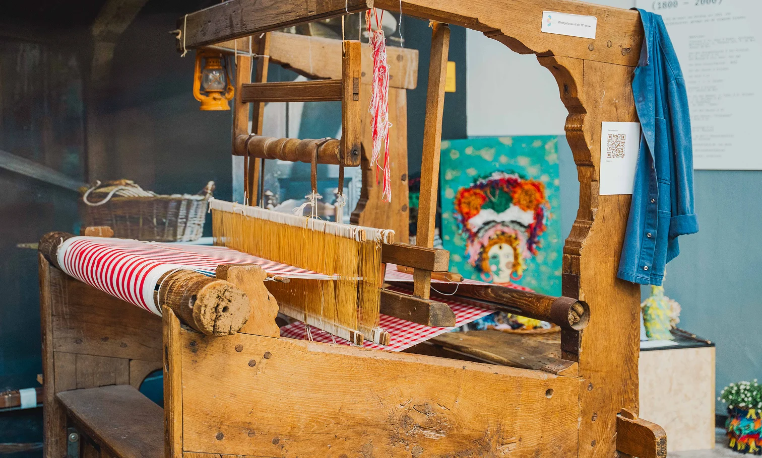Historisch houten weefgetouw met rood-wit geweven stof in het Weverijmuseum